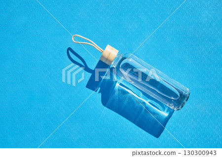 Reusable glass water bottle on blue mat Reusable glass water bottle on blue mat 130300943