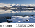 Snow covered coast of Norwegian fjord near Troms at Christmas time. A sunny winter day in Northern Norway above the Arctic Circle 130301260