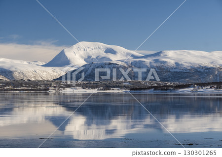 Snow covered coast of Norwegian fjord near Troms at Christmas time. A sunny winter day in Northern Norway above the Arctic Circle 130301265