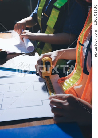 Closeup of team of industrial engineers meeting analyze machinery blueprints consult project on table in manufacturing factory. Working in manufacturing plant or production plant. Closeup of team of industrial engineers meeting analyze machinery blueprints consult project on table in manufacturing factory. Working in manufacturing plant or production plant. 130301630