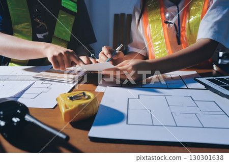 Closeup of team of industrial engineers meeting analyze machinery blueprints consult project on table in manufacturing factory. Working in manufacturing plant or production plant. 130301638