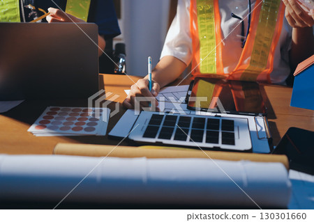 Closeup of team of industrial engineers meeting analyze machinery blueprints consult project on table in manufacturing factory. Working in manufacturing plant or production plant. Closeup of team of industrial engineers meeting analyze machinery blueprints consult project on table in manufacturing factory. Working in manufacturing plant or production plant. 130301660