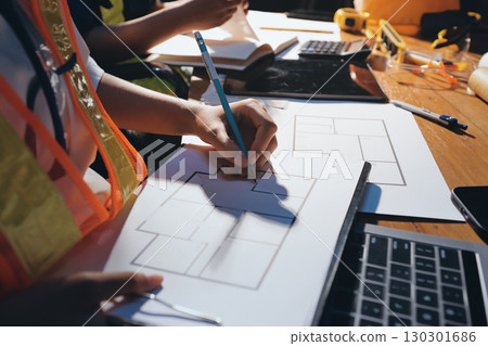 Closeup of team of industrial engineers meeting analyze machinery blueprints consult project on table in manufacturing factory. Working in manufacturing plant or production plant. Closeup of team of industrial engineers meeting analyze machinery blueprints consult project on table in manufacturing factory. Working in manufacturing plant or production plant. 130301686