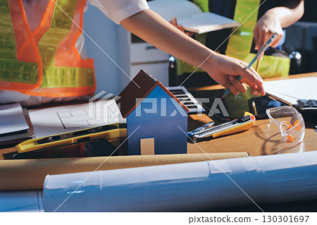 Closeup of team of industrial engineers meeting analyze machinery blueprints consult project on table in manufacturing factory. Working in manufacturing plant or production plant. Closeup of team of industrial engineers meeting analyze machinery blueprints consult project on table in manufacturing factory. Working in manufacturing plant or production plant. 130301697