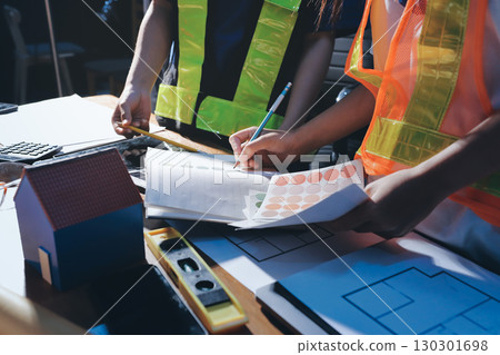 Closeup of team of industrial engineers meeting analyze machinery blueprints consult project on table in manufacturing factory. Working in manufacturing plant or production plant. Closeup of team of industrial engineers meeting analyze machinery blueprints consult project on table in manufacturing factory. Working in manufacturing plant or production plant. 130301698