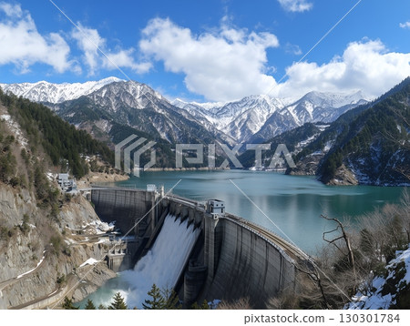 翠綠的湖泊和巨大的水壩在雄偉的雪山背景下排出大量水的壯觀景色。 130301784