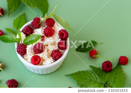 Cottage cheese with raspberries and green leaves on a green background 130301855