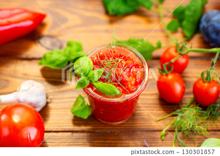 Glass of tomato sauce surrounded by garlic vegetables 130301857