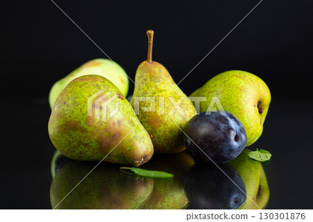 Ripe pears and plums on a black background 130301876