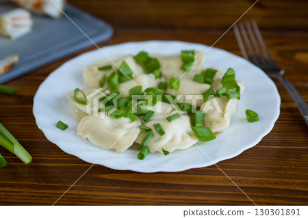 Appetizing dumplings with potatoes and onions on a rustic table 130301891