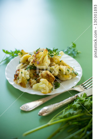 Fried cauliflower with spices and herbs on a green background 130301893