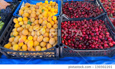 Fresh apricots and cherries displayed in black crates at market. Nutrition, agriculture, and seasonal harvest with natural fruit lifestyle. Fresh apricots and cherries displayed in black crates at market. Nutrition, agriculture, and seasonal harvest with natural fruit lifestyle. 130302201