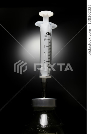 The needle of the syringe pierced the rubber membrane of the vaccine solution bottle 130302325