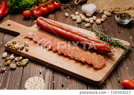 Sliced gourmet sausage with pistachios on wooden board with herbs and vegetables Sliced gourmet sausage with pistachios on wooden board with herbs and vegetables 130303017
