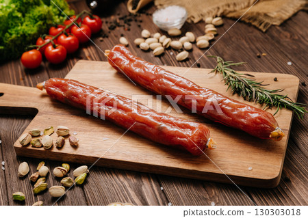 Smoked sausages with pistachios and rosemary on a wooden board, rustic kitchen background Smoked sausages with pistachios and rosemary on a wooden board, rustic kitchen background 130303018