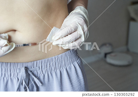 Young caucasian female administering insulin with syringe at home for diabetes 130303292