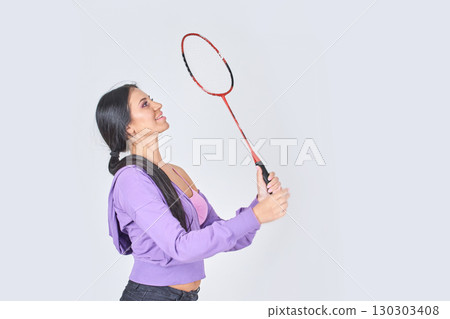 Young hispanic female playing badminton with red racket in casual purple outfit 130303408