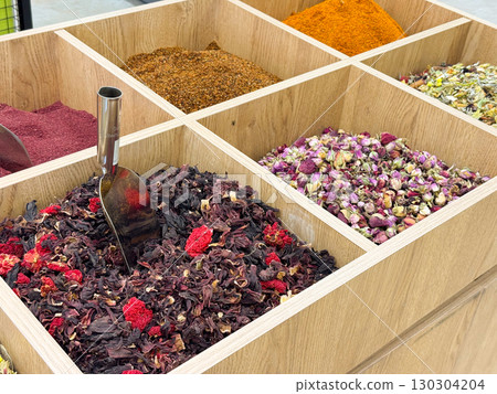Variety of colorful spices and dried herbs displayed in wooden boxes. Culinary culture, natural ingredients, and traditional oriental markets. 130304204