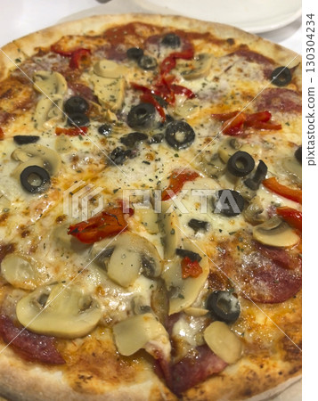 Savory pizza topped with mushrooms, olives, and peppers at a cozy restaurant Savory pizza topped with mushrooms, olives, and peppers at a cozy restaurant 130304234
