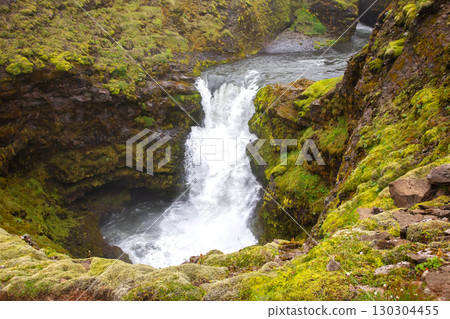 Majestic waterfall cascading into a green canyon in Iceland's dramatic landscape 130304455