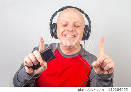 Man enjoying music and dancing with headphones in a bright indoor setting 130304465