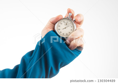 Hand holding a silver stopwatch in a blue sleeve while timing an activity indoors Hand holding a silver stopwatch in a blue sleeve while timing an activity indoors 130304489