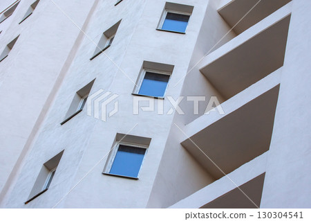 Modern apartment building exterior with geometric design and blue windows 130304541