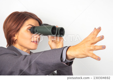 Businesswoman using binoculars to spot opportunities at a conference early in the day 130304692