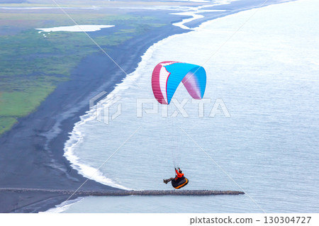 Paragliding over Iceland's stunning coast on a clear day with vibrant parachute colors Paragliding over Iceland's stunning coast on a clear day with vibrant parachute colors 130304727