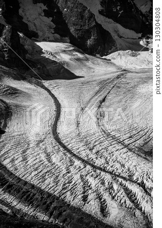 The majestic Pers Glacier, located in the Bernina Range of the Bundner Alps, showcases unique ice formations and crevasses under a captivating landscape. A true display of nature's power. 130304808
