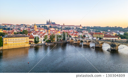 Bright colors fill the sky as the sun rises over Prague, illuminating the Vltava River and its medieval architecture. Bright colors fill the sky as the sun rises over Prague, illuminating the Vltava River and its medieval architecture. 130304809