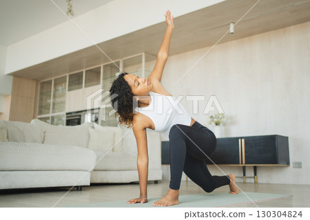 Yoga fitness workout training. Healthy African girl practicing yoga at home. Woman training Pilates doing sports exercise on yoga mat indoor. Girl have training workout for weight loss. Sport fitness 130304824