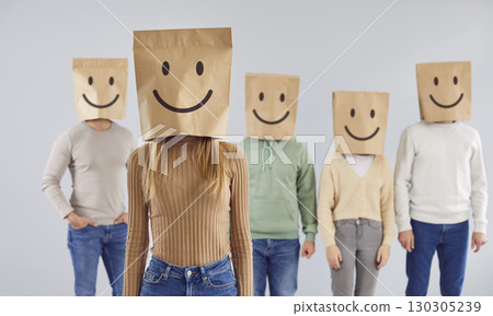 Woman with paper bag with smiley face over head and group of people wearing same bags in background Woman with paper bag with smiley face over head and group of people wearing same bags in background 130305239