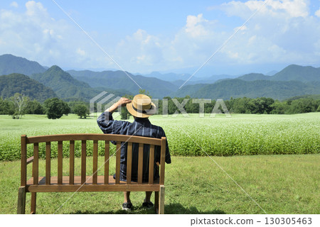 An old man resting on a bench in a buckwheat field An old man resting on a bench in a buckwheat field 130305463