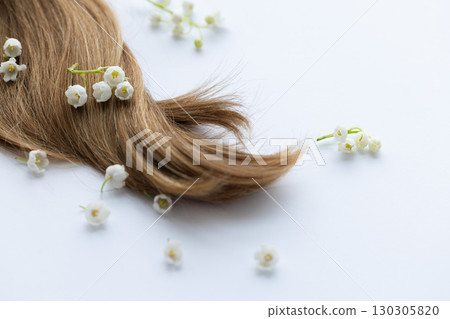 Female hair and lily of the valley flowers. On a white background. Female hair and lily of the valley flowers. On a white background. 130305820