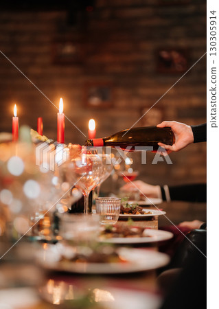 Hand pouring red wine at cozy candlelit dinner with gourmet food and elegant decor 130305914