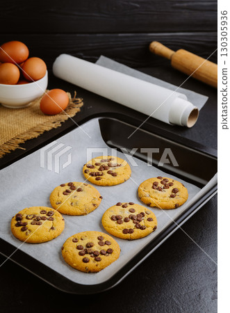 Freshly baked chocolate chip cookies on a baking tray with parchment paper Freshly baked chocolate chip cookies on a baking tray with parchment paper 130305936
