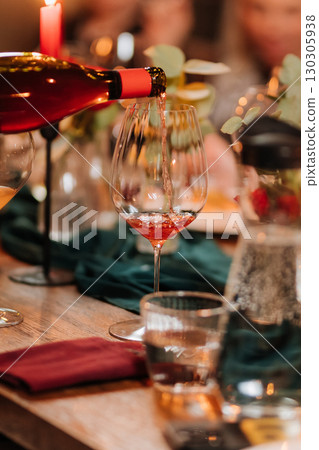 Sommelier pouring red wine during elegant dinner with warm candlelight ambiance 130305938