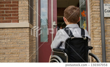 A first-grader in a wheelchair in front of the school entrance, symbolizing accessibility, inclusivity, and equal opportunities in education 130307058
