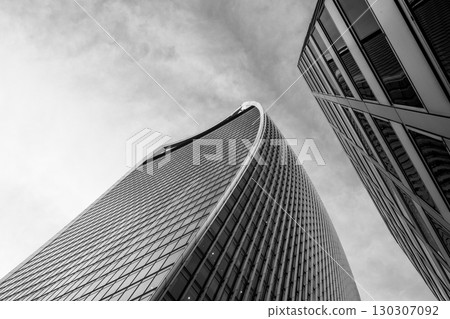 Modern architecture stands prominently against a cloudy sky in London. The Fenchurch Building, known for its distinctive shape, towers among other structures in the bustling city. 130307092