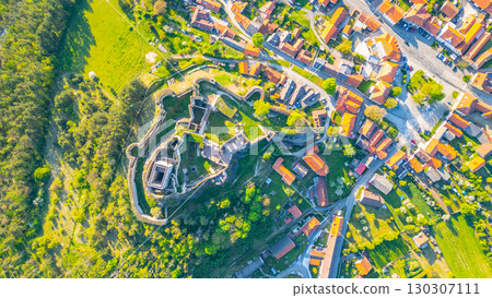 Aerial view captures the impressive Rabi Castle ruins nestled among the lush greenery, overlooking nearby village homes in Czechia. The landscape reveals historical architecture and scenic beauty. Aerial view captures the impressive Rabi Castle ruins nestled among the lush greenery, overlooking nearby village homes in Czechia. The landscape reveals historical architecture and scenic beauty. 130307111