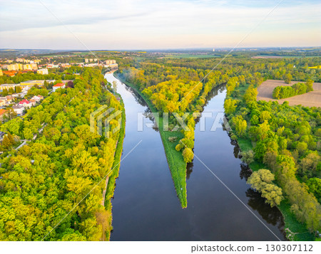 Vibrant greenery lines the banks where the Vltava and Labe rivers meet near Melnik, Czechia. This aerial view showcases the natural beauty and winding pathways of the rivers. 130307112