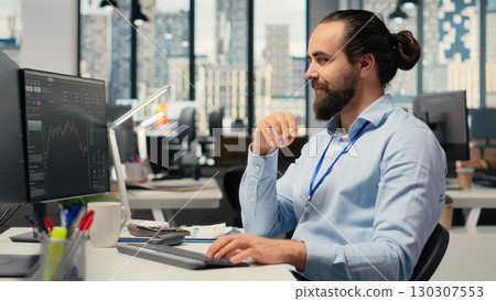 Trader in office doing brainstorming before committing to investment, smiling, expressing trust in choice. Brokerage company expert thinking before trading, showing self assurance Trader in office doing brainstorming before committing to investment, smiling, expressing trust in choice. Brokerage company expert thinking before trading, showing self assurance 130307553