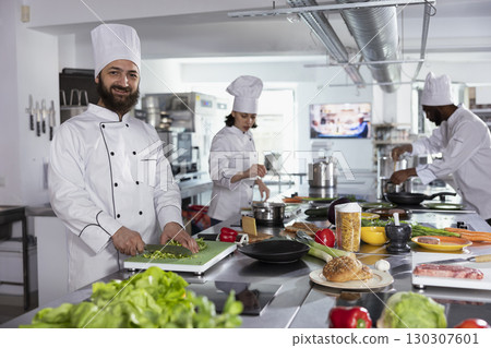 In a professional kitchen, male cook preparing gourmet meals by using cutting boards and chopping ingredients. Chef cooking with fresh produce, doing food prep for tasty dishes, gastronomy. In a professional kitchen, male cook preparing gourmet meals by using cutting boards and chopping ingredients. Chef cooking with fresh produce, doing food prep for tasty dishes, gastronomy. 130307601