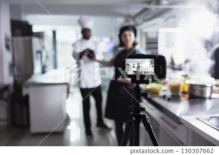 Woman expert provides professional cooking techniques for web master class. With a camera filming every step, the culinary school lesson brings gourmet skills to a global audience. 130307662