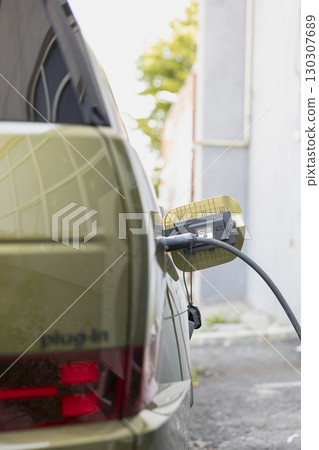 Closeup of electric vehicle being charged at EVSE station, showcasing green energy transportation. EV car with connected plug being recharged, concept of zero emissions tech 130307689