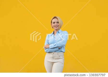 Smiling young blond businesswoman crossing arms 130307797