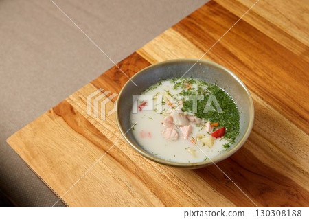 Indulge in a bowl of delicious Coconut Soup, enriched with fresh herbs and tender chicken 130308188