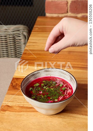 Garnishing a Vibrant Beetroot Soup beautifully with Fresh Herbs for a delightful presentation Garnishing a Vibrant Beetroot Soup beautifully with Fresh Herbs for a delightful presentation 130308206
