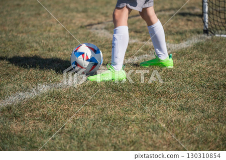 Youth soccer player prepares to kick a ball on a sunny day at a local sports field 130310854